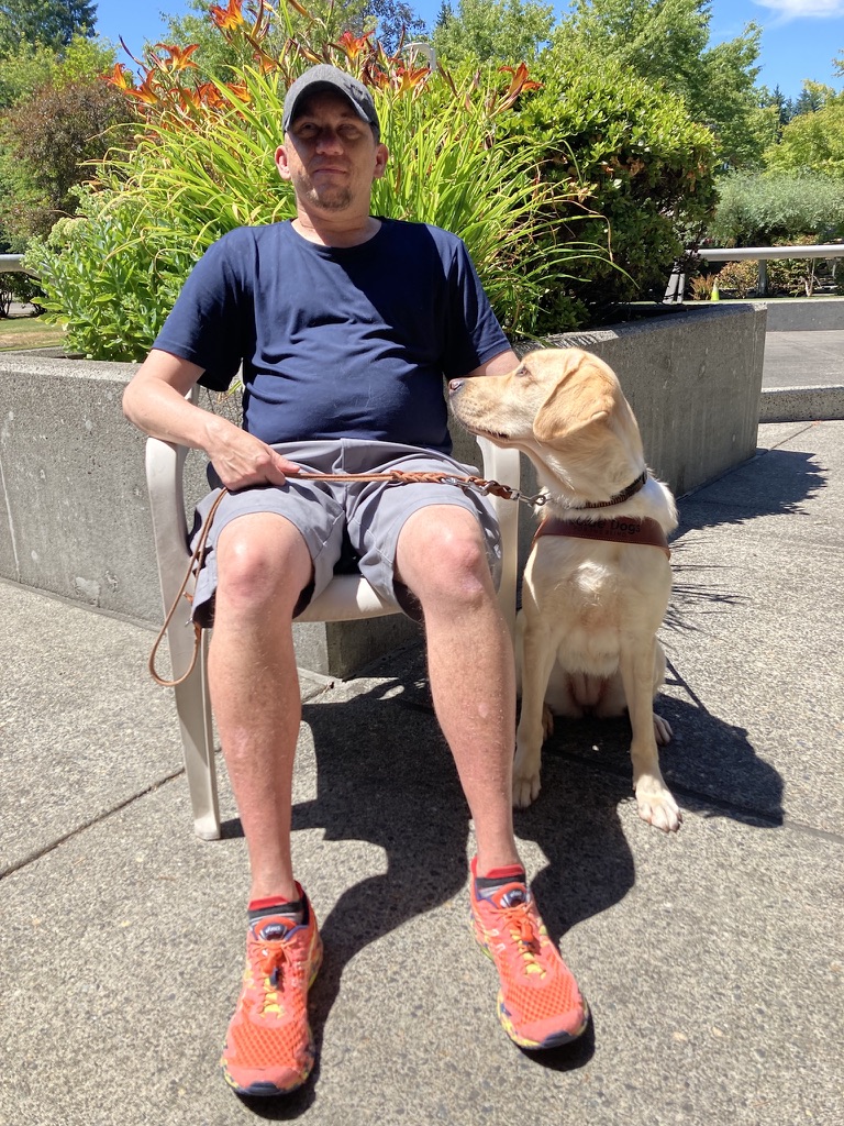 Ed and his guide dog Helen sitting outside at the GDB campus.