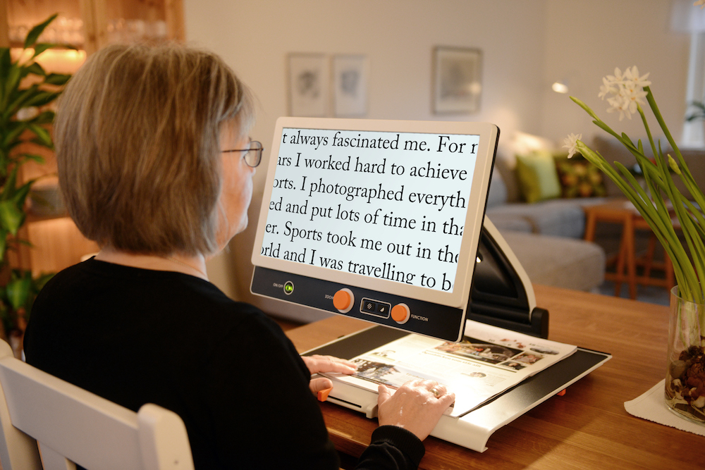 Low Vision International - Zip 17 Premium, portable magnifier. A Woman reading a book under the camera.