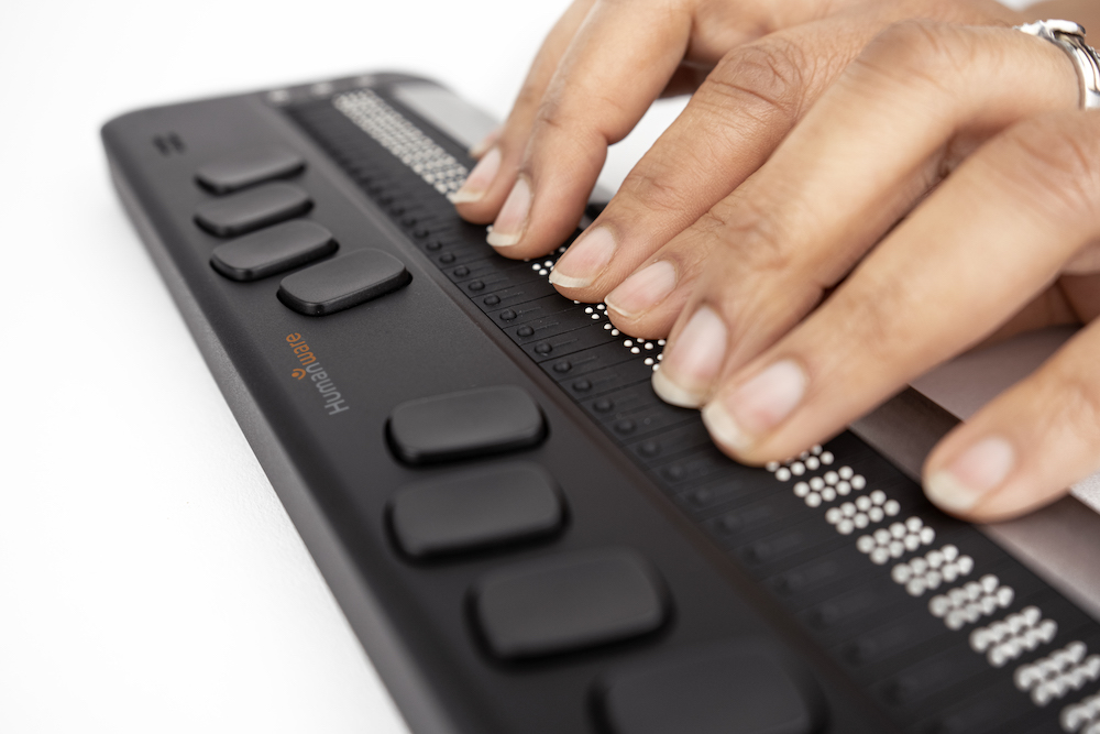 A pair of hands using a Brailliant 40X braille display.