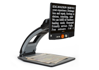 Humanware Reveal 16 desktop magnifier with a newspaper displayed on the screen.